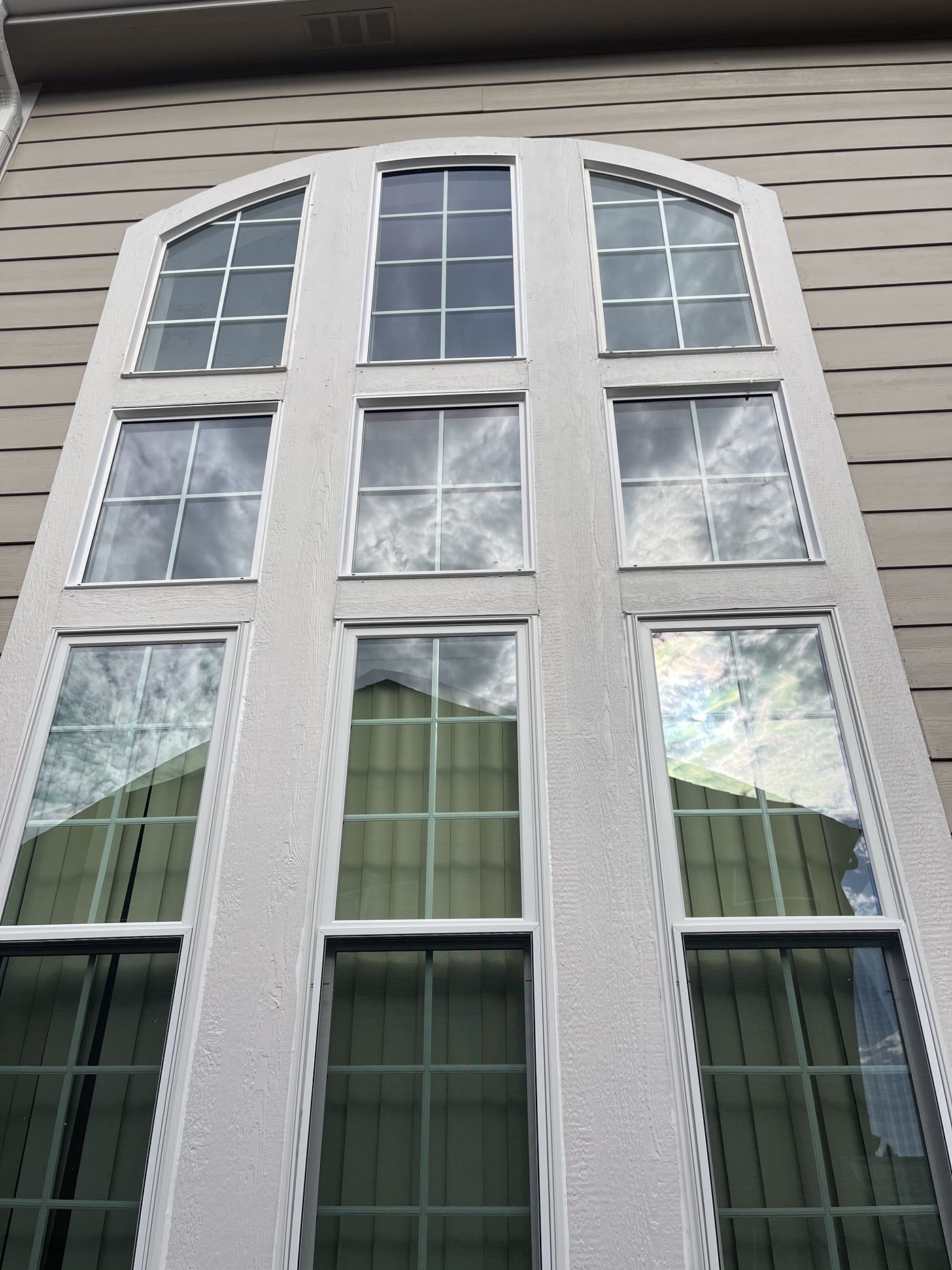 Tall arched multi-pane window on a stucco home, newly installed