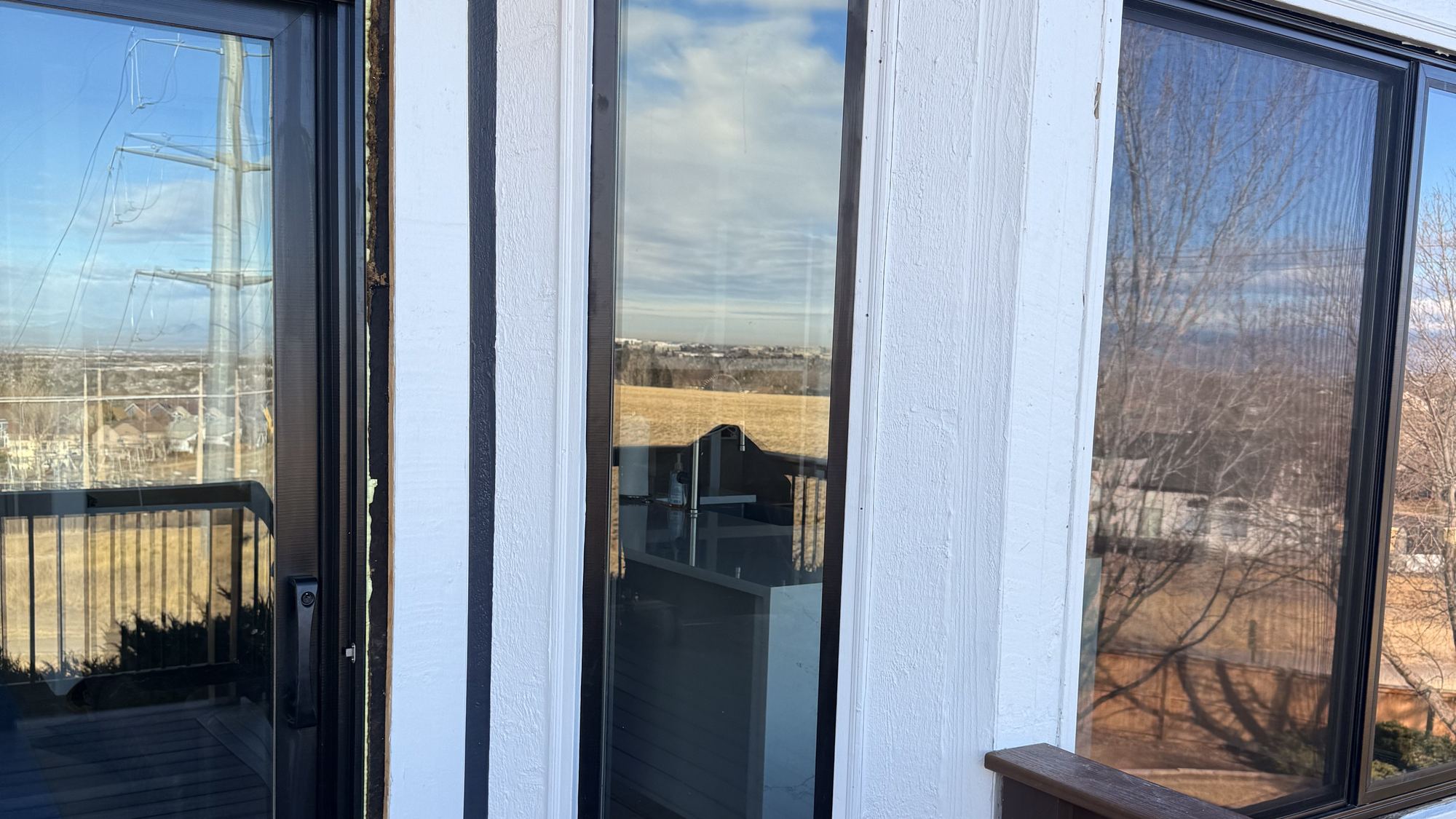 Black-frame picture window and door on a deck, Front Range foothills beyond