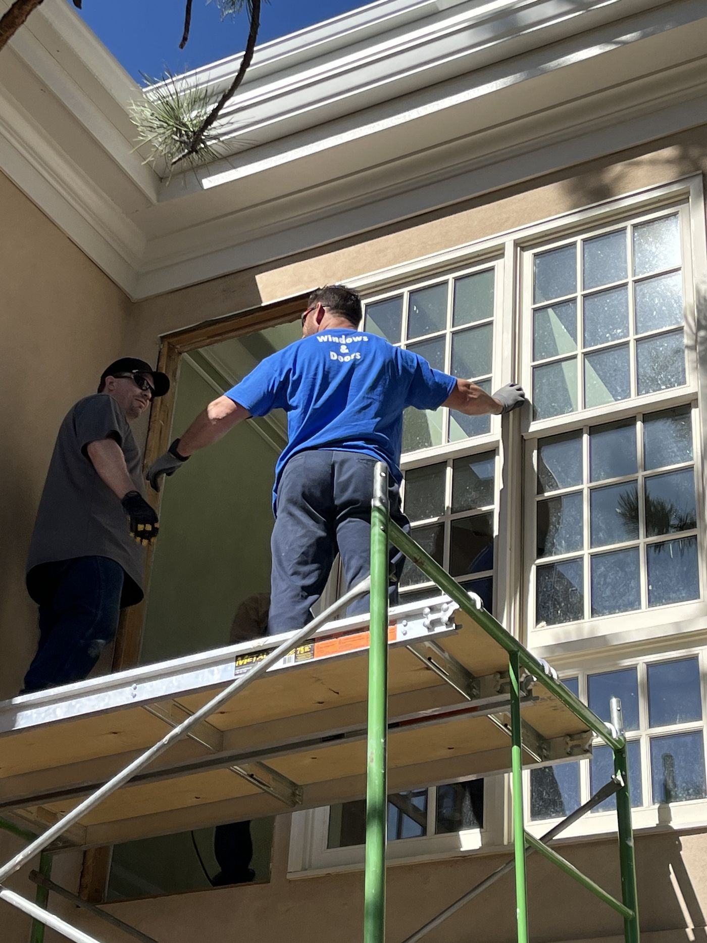 Two installers on scaffold setting a second-story window