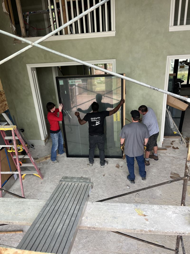 Four installers carrying a glass door panel