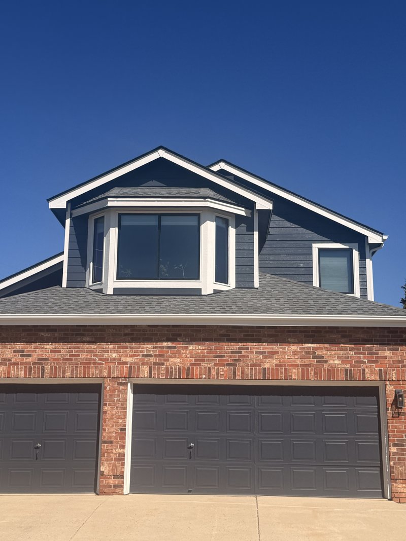 Navy two-story home with a new bay window over a brick garage