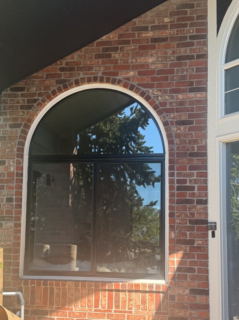 Black-frame arched window set in a brick arch
