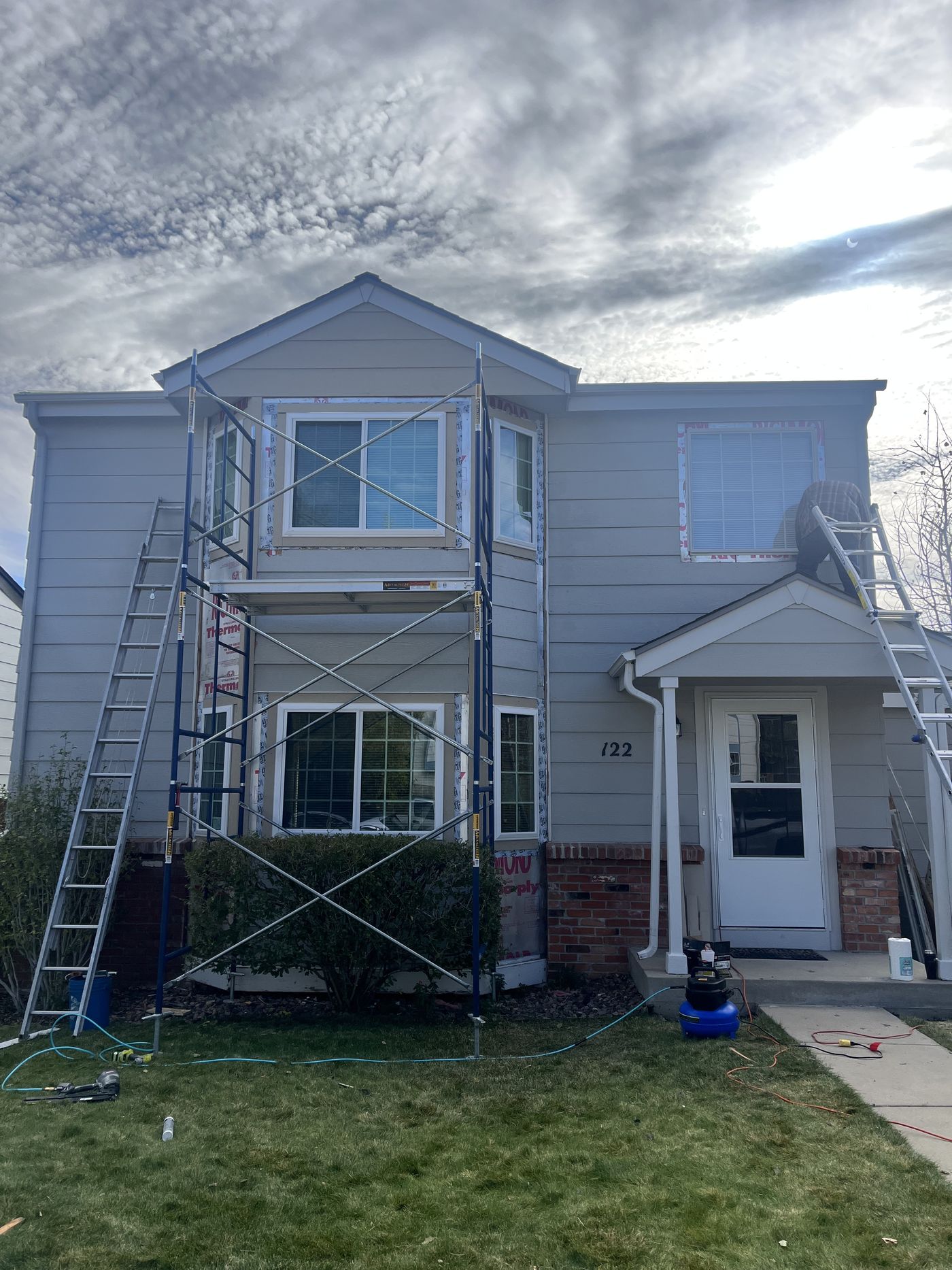 Two-story house with scaffold during window replacement